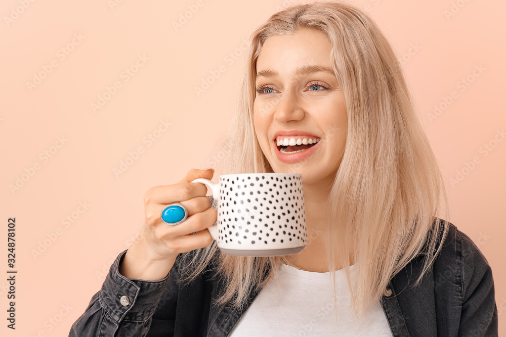 Beautiful young woman with tea on color background