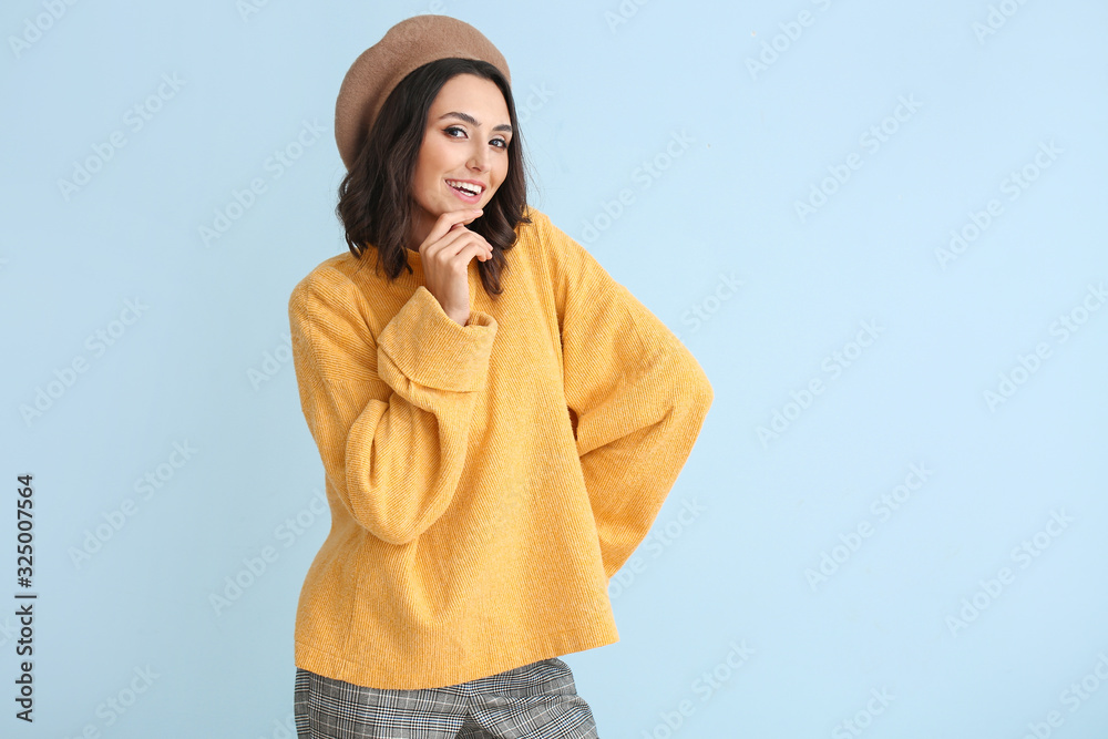 Beautiful young woman in warm sweater on color background