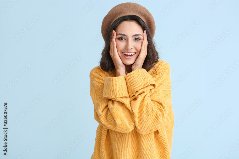 Beautiful young woman in warm sweater on color background