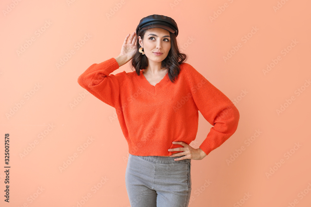 Beautiful young woman in warm sweater on color background