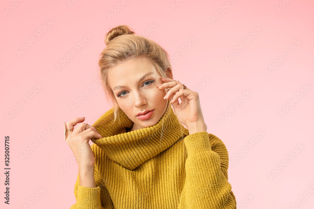 Young woman in warm sweater on color background