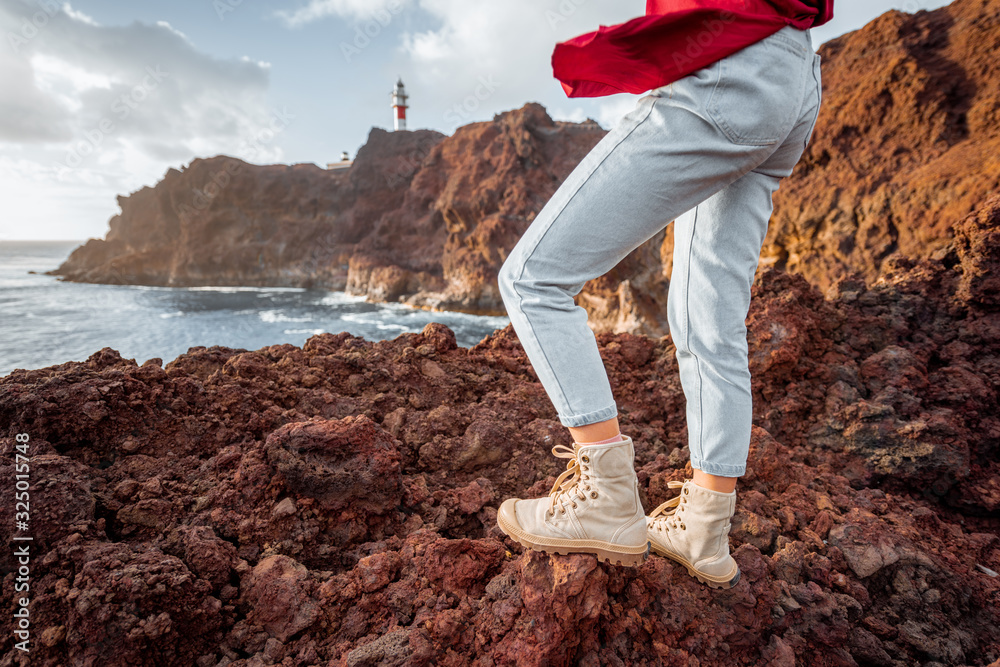 Traveler standing on the rocky land, traveling volcanic landsacpes near the lighthouse. View on the 