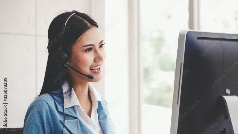 Customer support agent or call center with headset works on desktop computer while supporting the cu