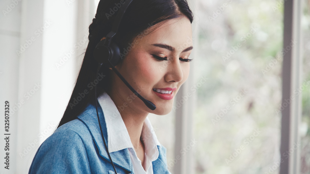 Customer support agent or call center with headset works on desktop computer while supporting the cu