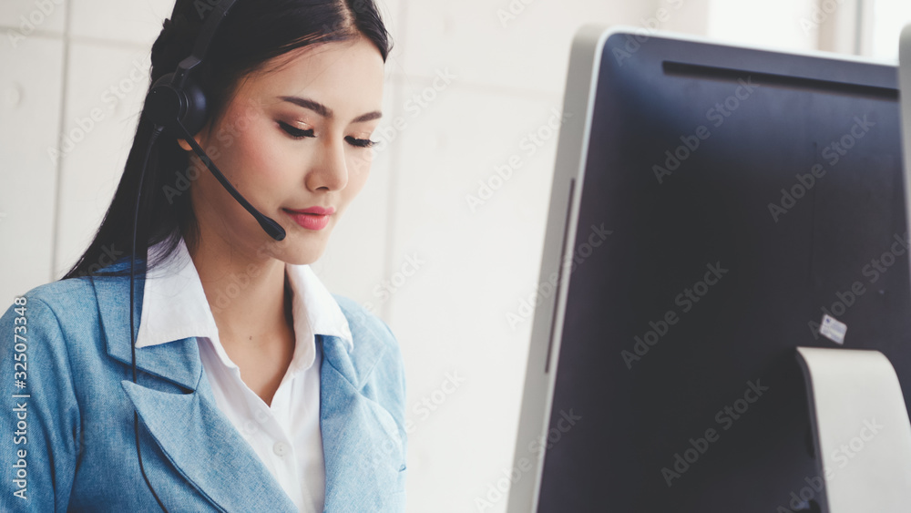 Customer support agent or call center with headset works on desktop computer while supporting the cu