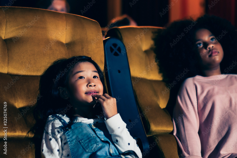 Three children having fun and enjoy watching movie in cinema