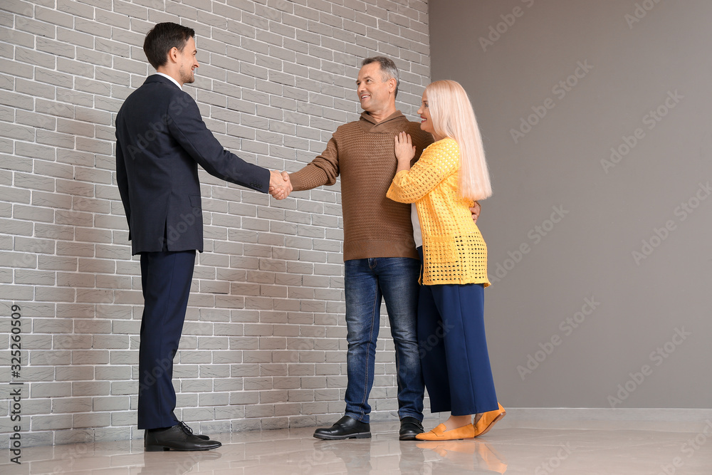 Male real estate agent working with mature couple indoors