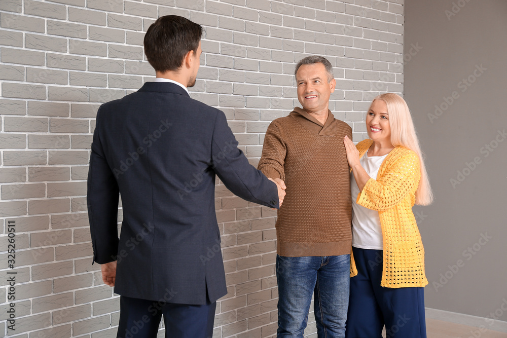 Male real estate agent working with mature couple indoors