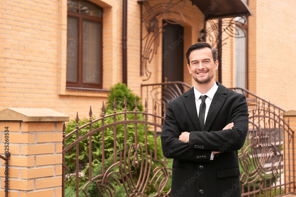 Male real estate agent near house for sale outdoors