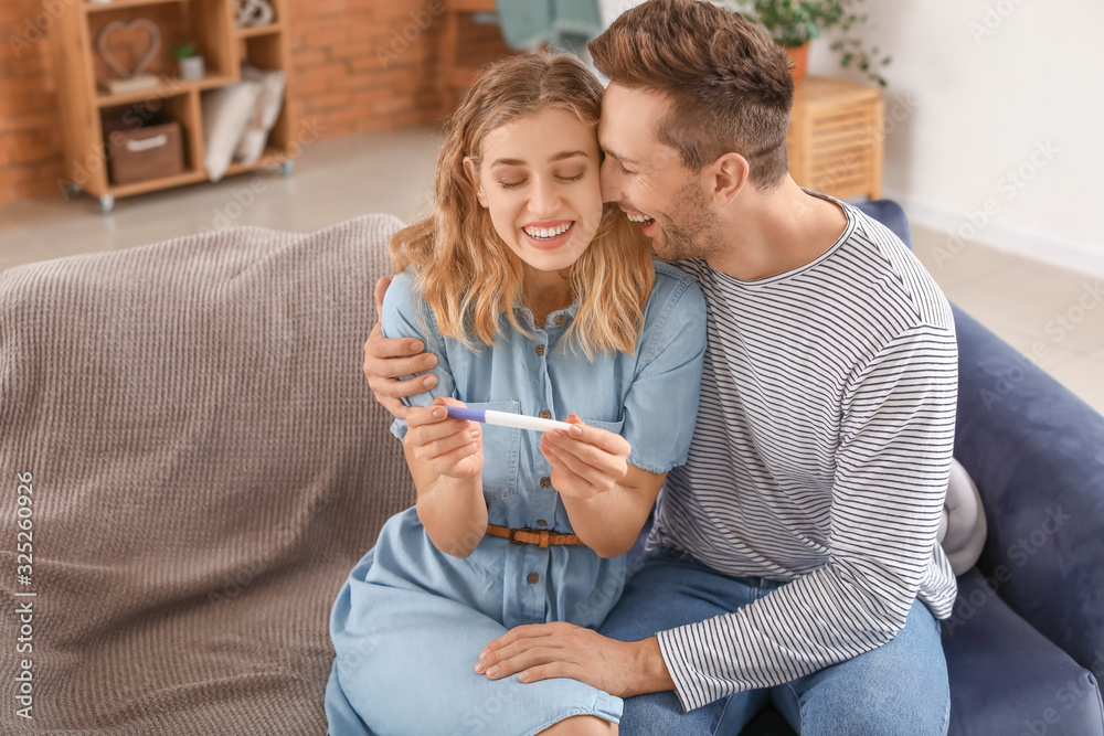 Happy young couple with pregnancy test at home