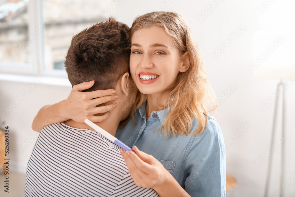 Happy young couple with pregnancy test at home