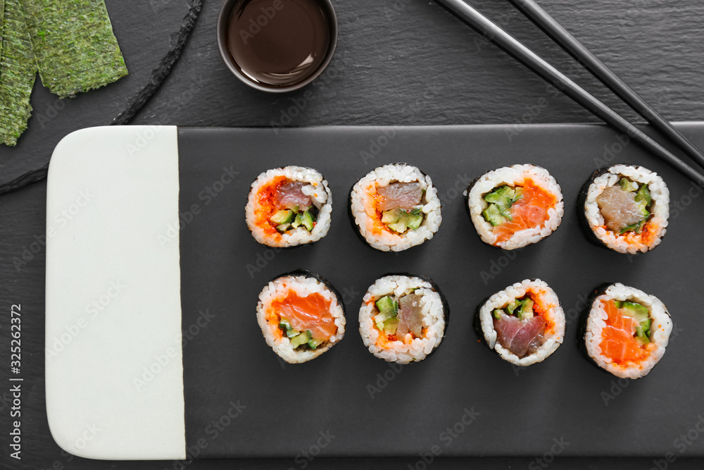 Plate with tasty sushi rolls on table