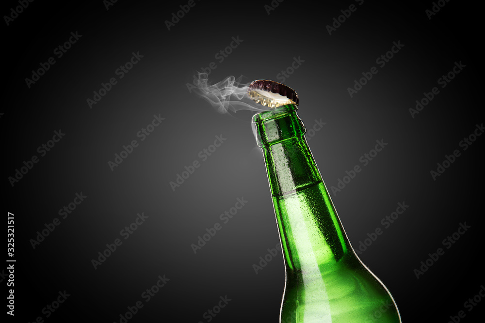 Cold wet bottle of chilled drink with drops. Opening of beer cap with the gas output.