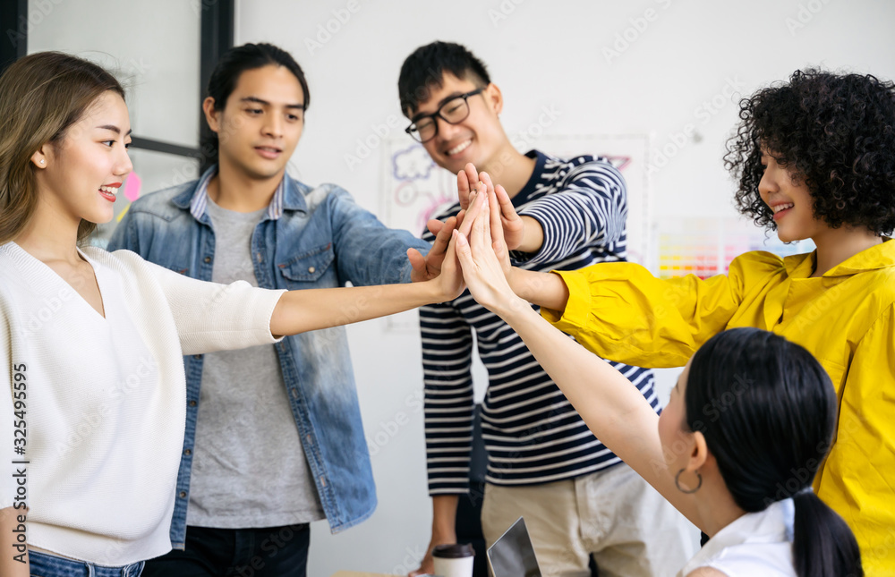 Young Asian creative business team  giving a high fives gesture teamwork togetherness collaboration 