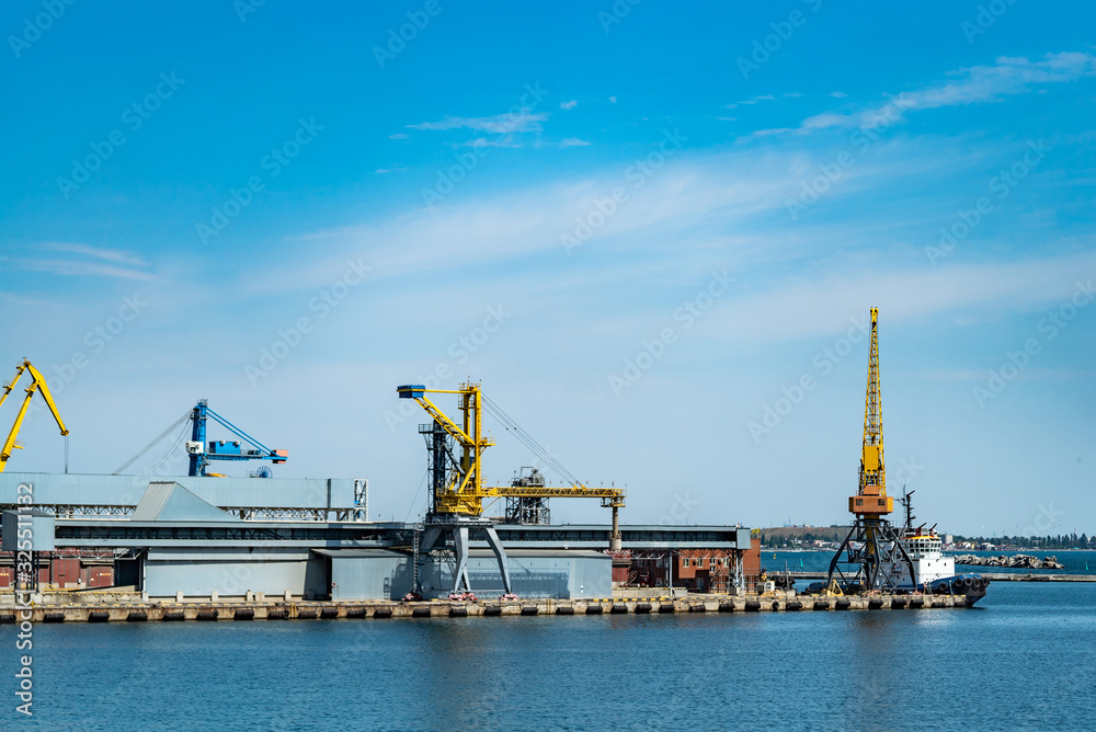 Panorama of the port cranes. Sea port with cranes and docks at blue sky background.