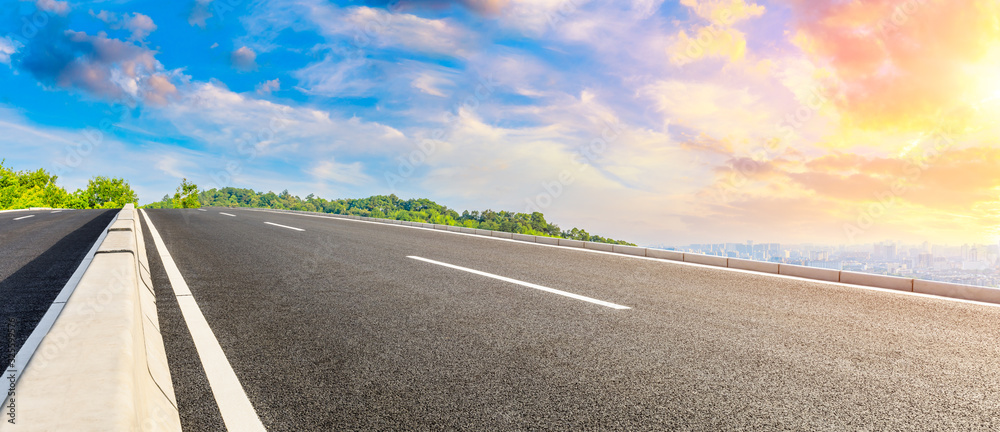 Empty asphalt road and city skyline with green mountain at sunrise in Hangzhou,China.