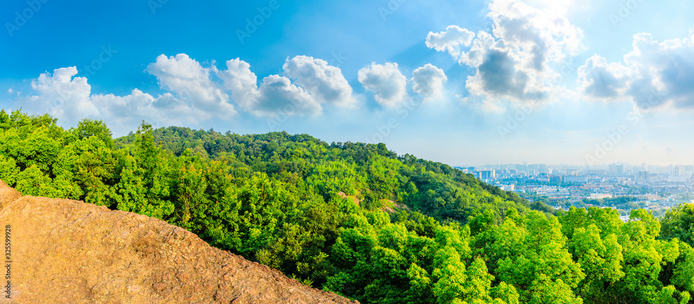 Green mountains and city skyline on a sunny day.