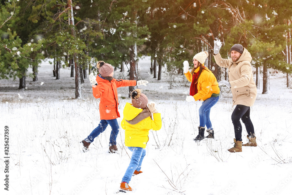 Happy family playing snowballs in park on winter day