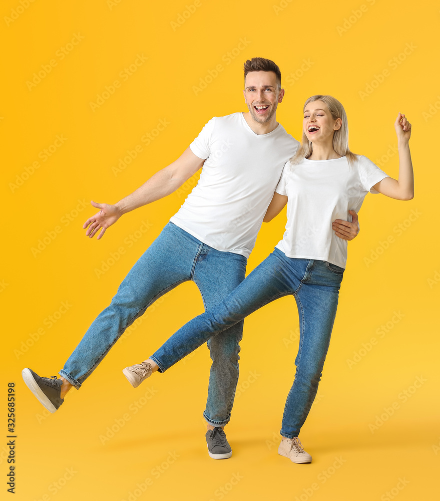 Happy dancing young couple on color background