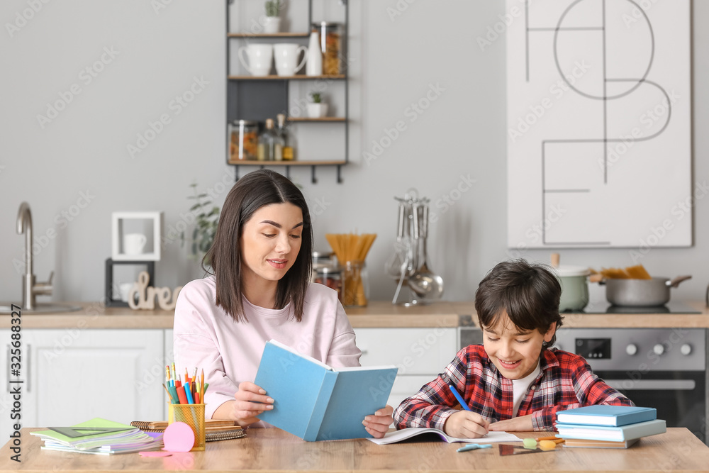 Little boy with his mother doing homework in kitchen