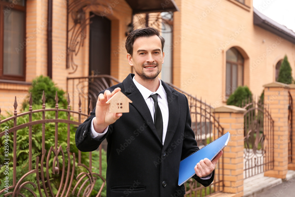 Male real estate agent near house for sale outdoors