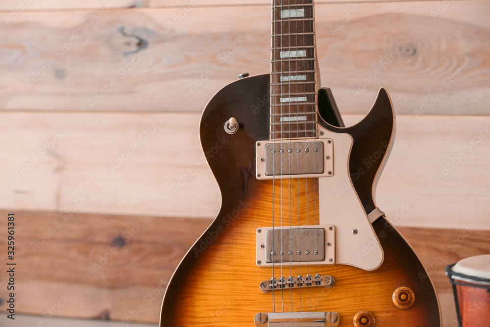 Modern guitar near wooden wall