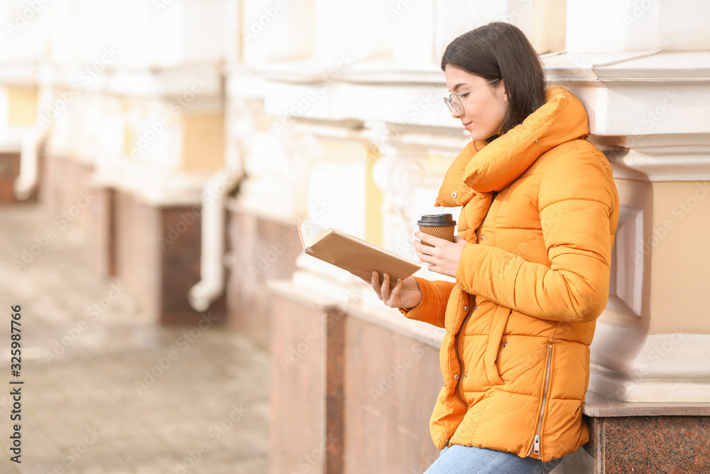 Young woman reading book outdoors