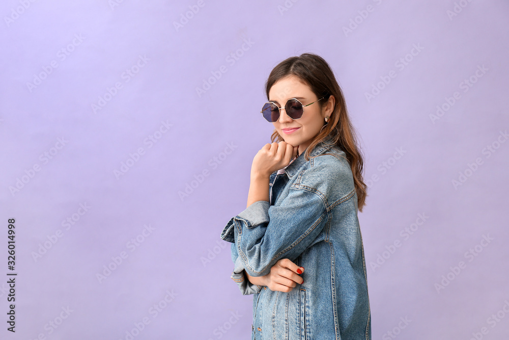 Young woman with stylish sunglasses on color background