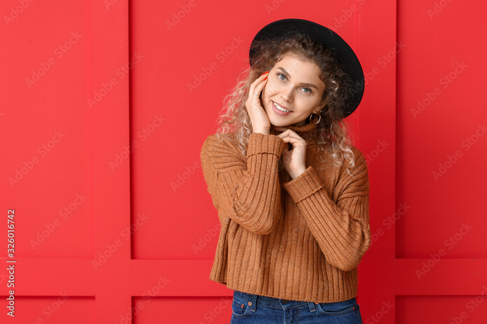 Beautiful young woman in warm sweater on color background