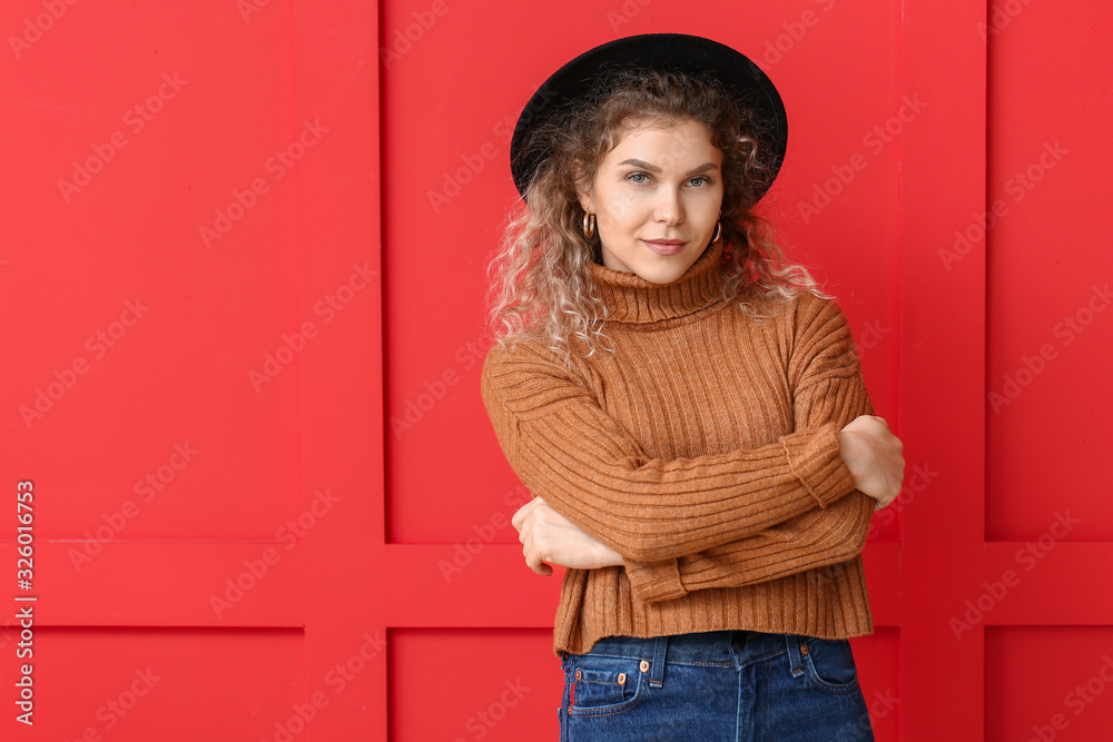 Beautiful young woman in warm sweater on color background