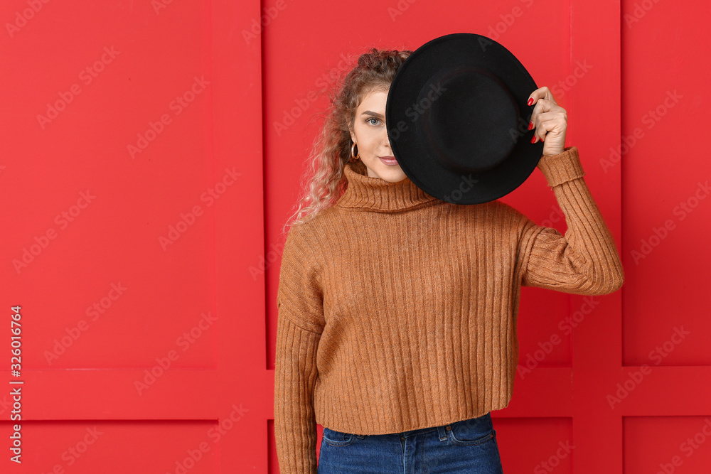 Beautiful young woman in warm sweater on color background