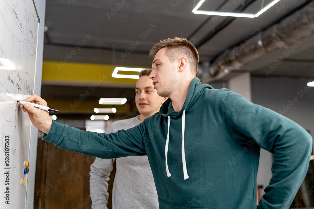 Man posing near flipchart in the office. A businessman in stress standing near a flip chat room. A m