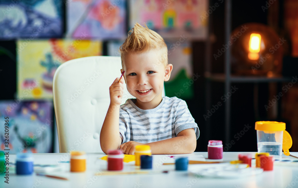 funny child boy draws laughing   with paint.