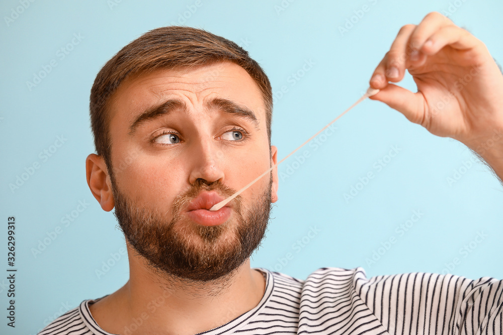 Funny man with chewing gum on color background