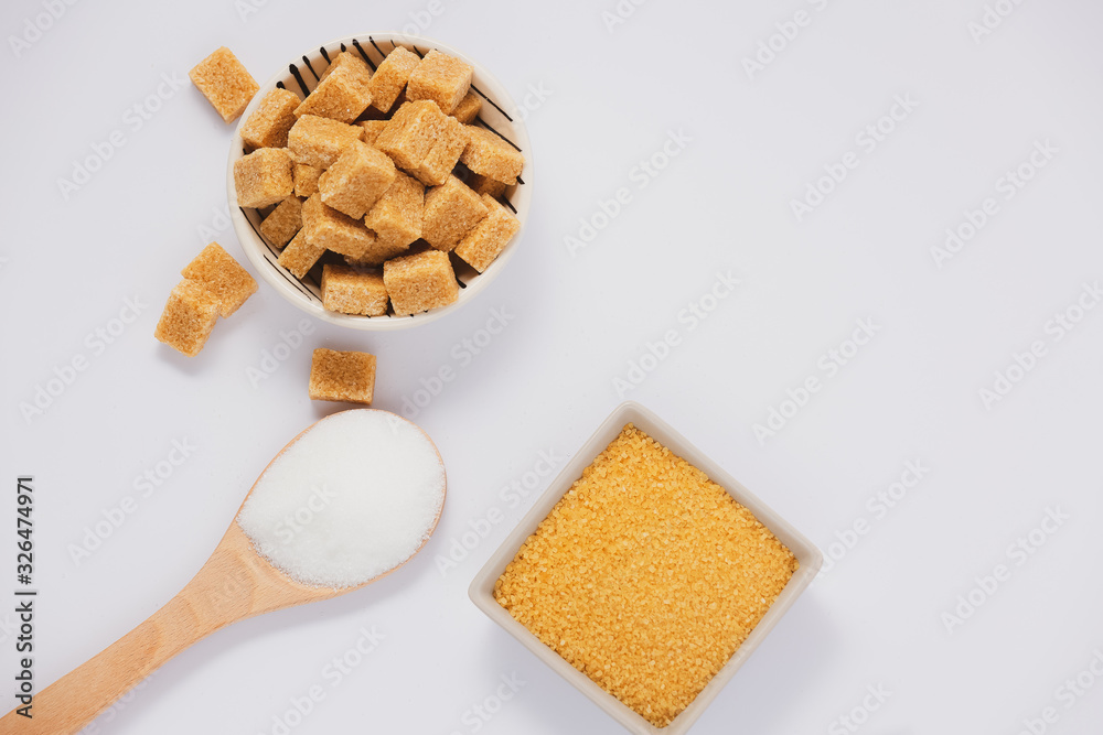 Brown sugar in a round glass cup and wooden spoon on a white background, healthy sugar is used for c