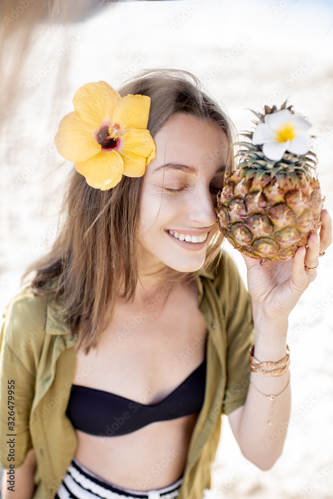 Facial portrait of a cute summer girl with pineapple fruit at the beach resort on a sunny day. Conce