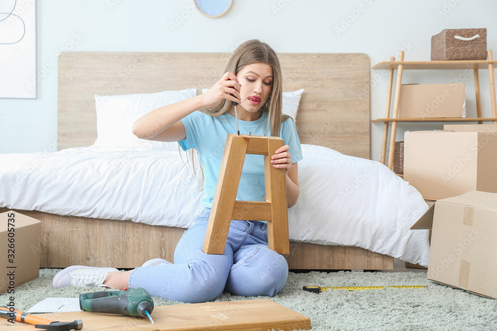 Young woman assembling furniture at home