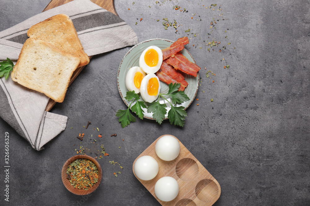 Plate with boiled eggs, bacon and toasted bread on dark background