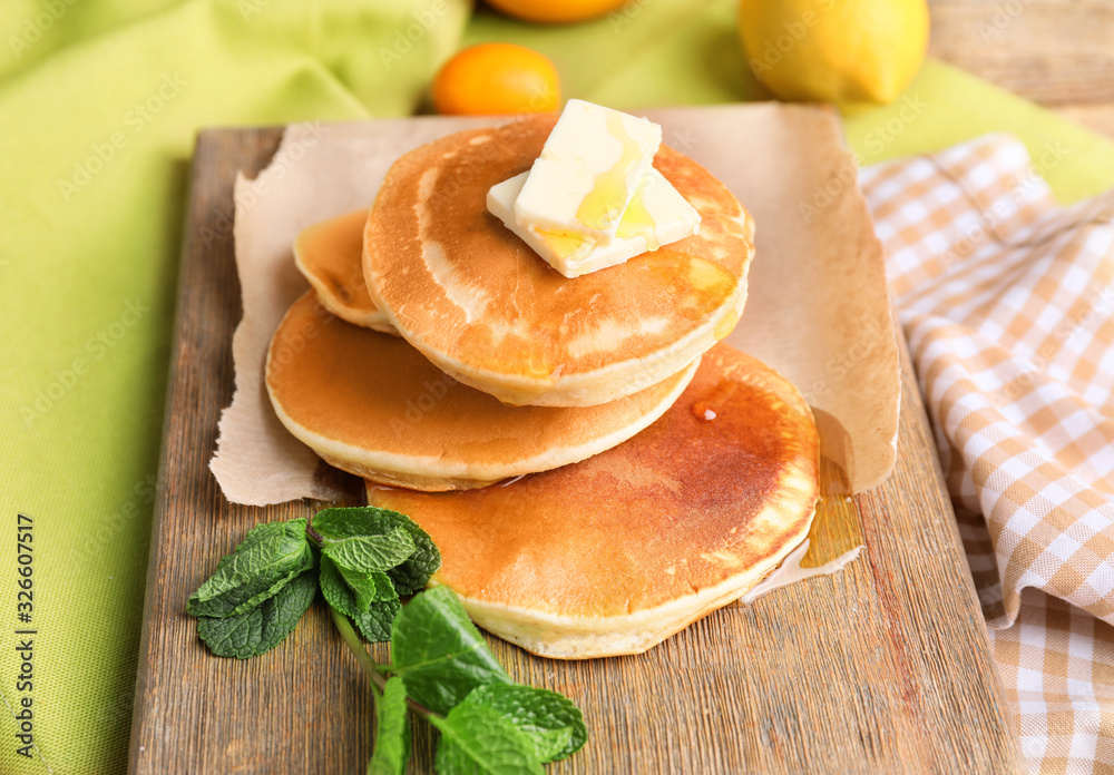 Tasty pancakes with honey and butter on board