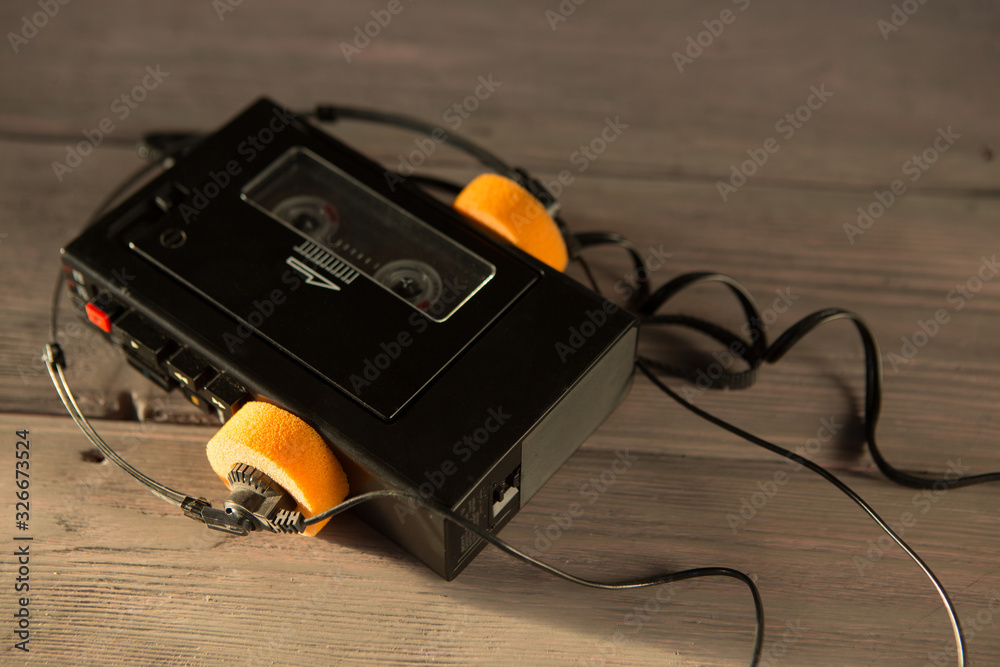 Old portable cassette player and headphones on a wooden background