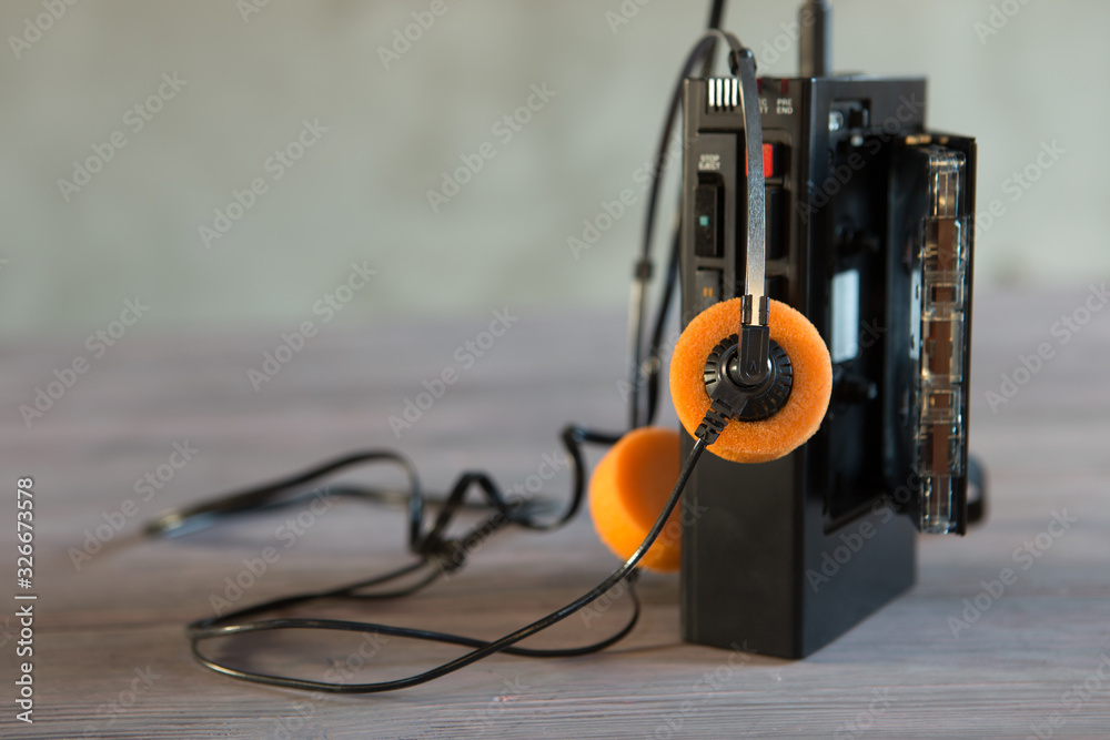 Old portable cassette player and headphones on a wooden background