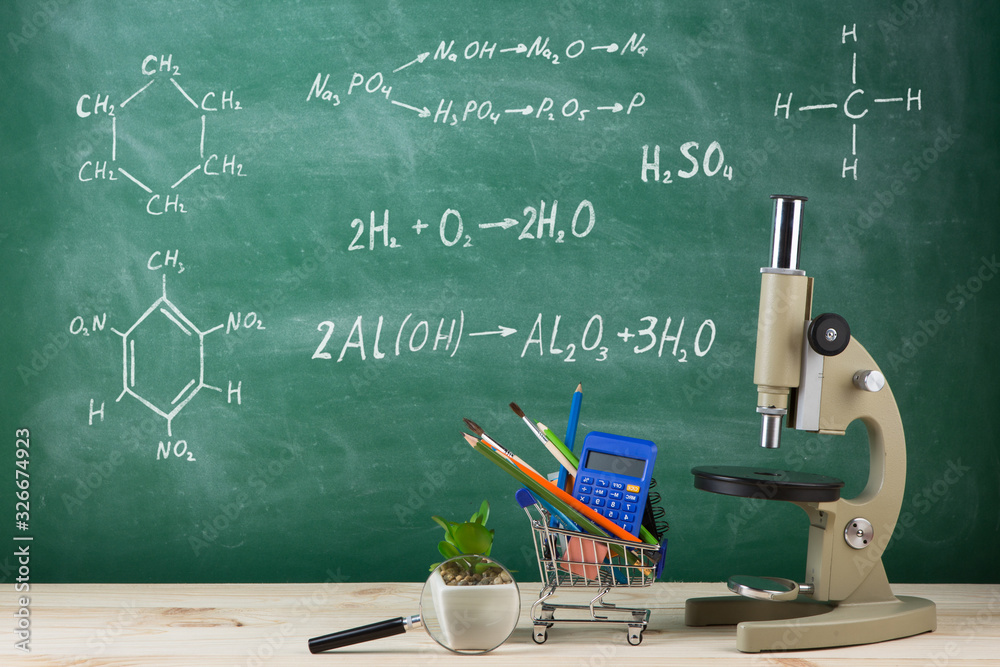 Education concept - microscope on the desk in the auditorium, blackboard background