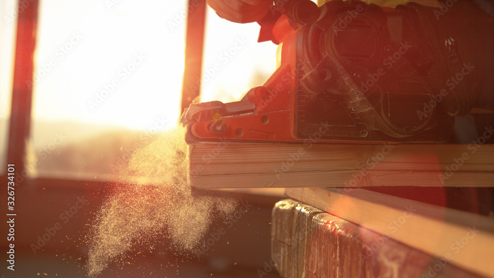 MACRO: Unrecognizable carpenter buffs the side of a plank with electric sander.