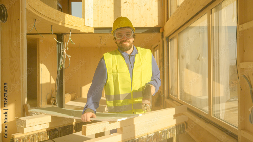 PORTRAIT: Young Caucasian builder smiles after cutting up a gypsum wallboard.