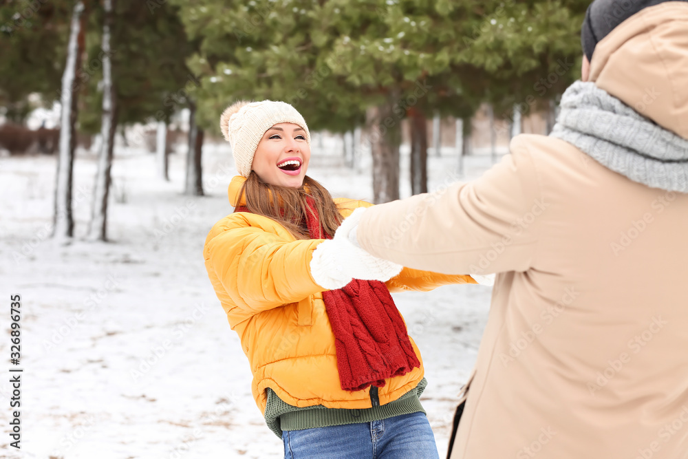 Happy young couple dancing in park on winter day