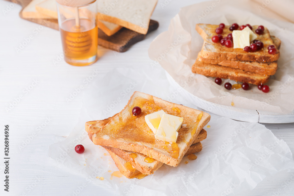 Tasty toasted bread with honey, butter and berries on table