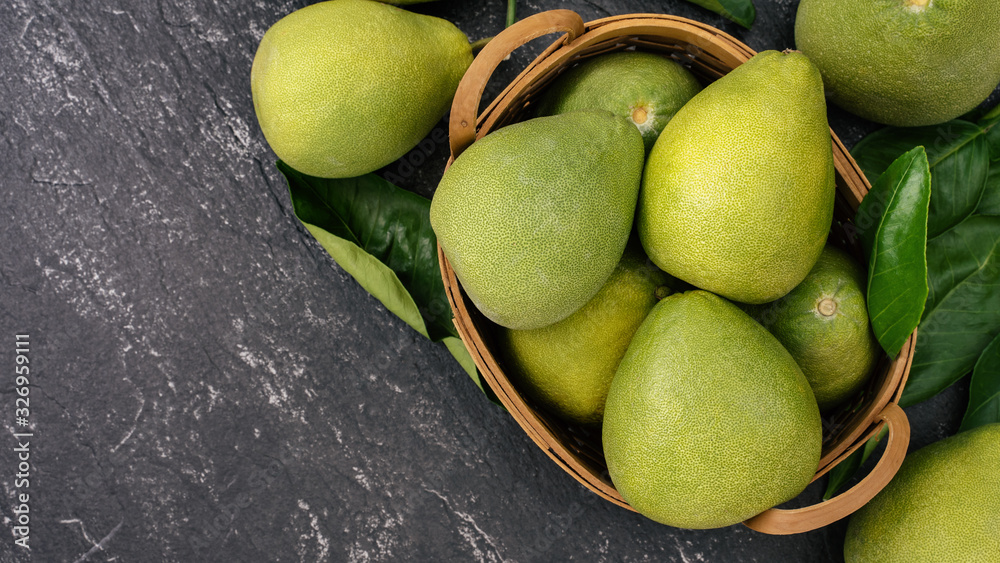 Fresh peeled pomelo, pummelo, grapefruit, shaddock on dark background in bamboo basket. Autumn seaso