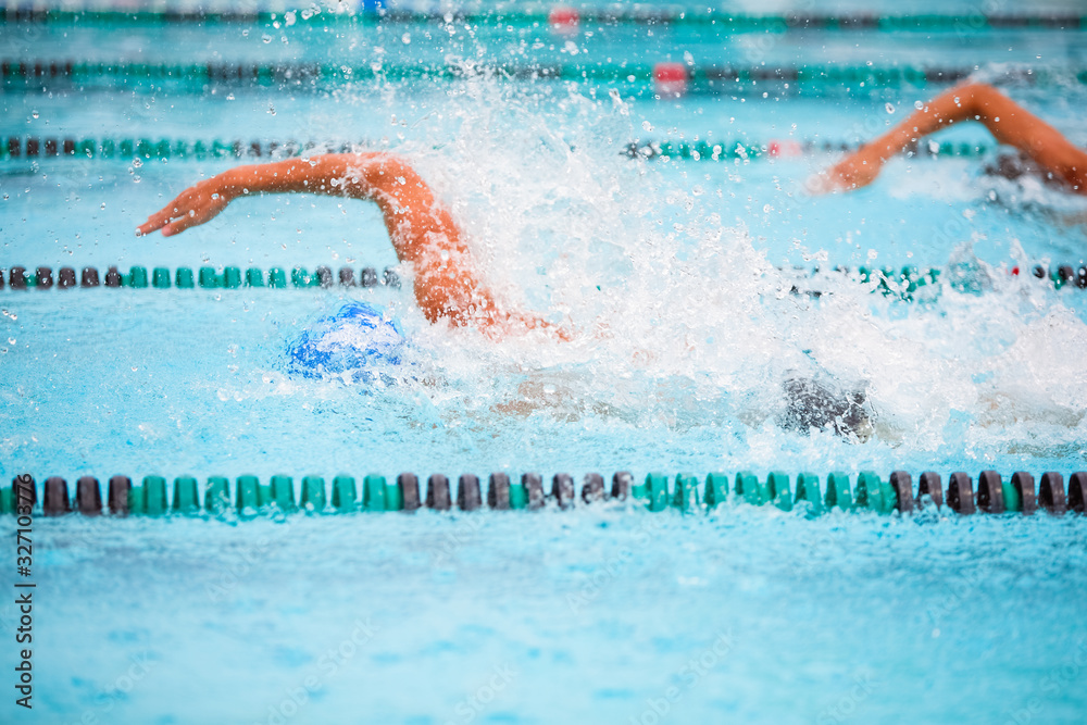 Motion blurred swimmers in a freestyle race, focus on water drops