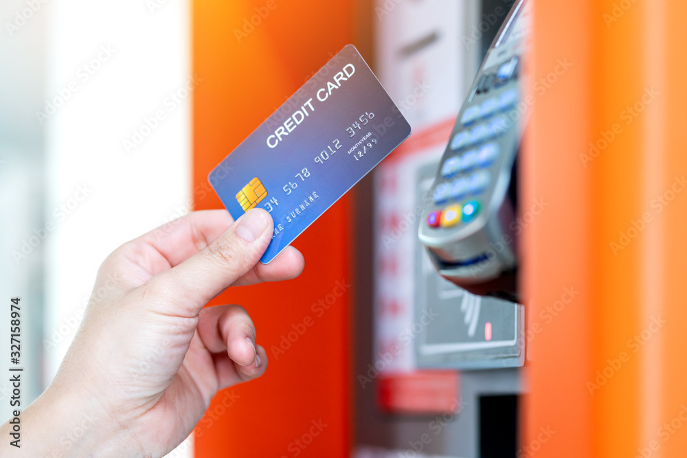 close up female hand swipe credit card to purchase something at paying machine blue bokeh background