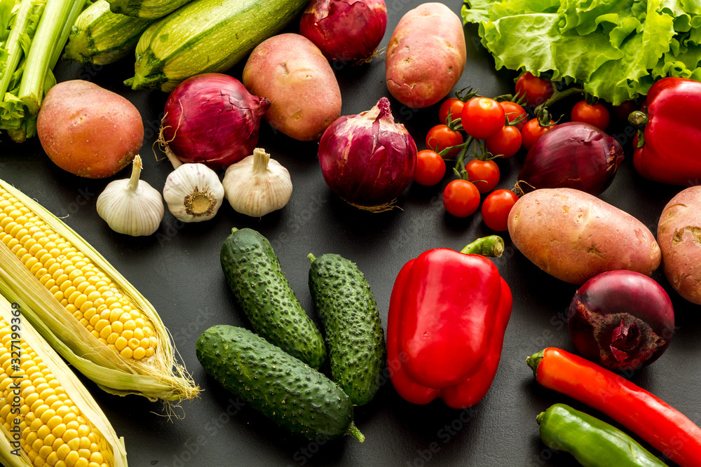 Fresh vegetables still life. Potato, cucumber, beet carrot, greenery on black background